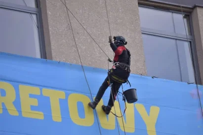 Prace na wysokości - montaż reklamy wielkoformatowej, przy zastosowaniu technik alpinistycznych, na budynku sklepu "Zenit" w Katowicach.