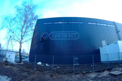 Malowanie loga na zewnętrznej ścianie hali produkcyjnej przy wykorzystaniu technik alpinistycznych.