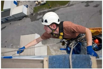 Malowanie logotypu na zewnętrznej elewacji budynku przy wykorzystaniu technik alpinistycznych.