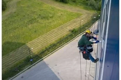 Malowanie logotypu na zewnętrznej elewacji budynku przy wykorzystaniu technik alpinistycznych.