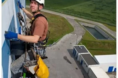 Malowanie logotypu na zewnętrznej elewacji budynku przy wykorzystaniu technik alpinistycznych.