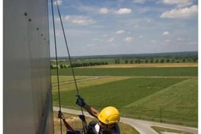 Malowanie logotypu na zewnętrznej elewacji budynku przy wykorzystaniu technik alpinistycznych.