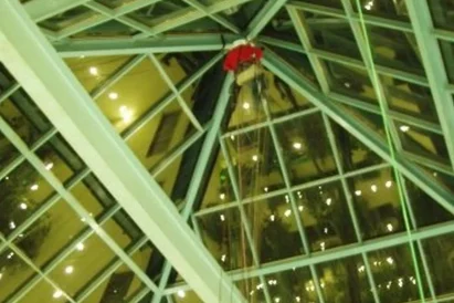 Mycie wewnętrznej i zewnętrznej powierzchni świetlika w kształcie piramidy przy wykorzystaniu technik alpinistycznych.
