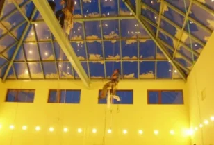Mycie wewnętrznej i zewnętrznej powierzchni świetlika w kształcie piramidy przy wykorzystaniu technik alpinistycznych.