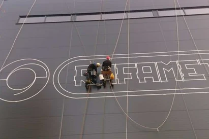 Malowanie loga na zewnętrznej ścianie hali produkcyjnej przy wykorzystaniu technik alpinistycznych.