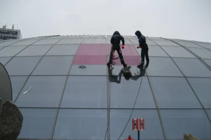 Wyklejanie reklamy na szklanej elewacji kopuły Ronda Sztuki.