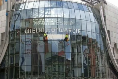 Wyklejanie reklamy przy użyciu techniki linowej na otwarcie Galerii Katowickiej.