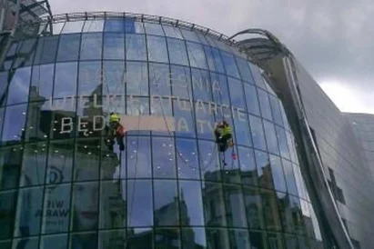 Wyklejanie reklamy przy użyciu techniki linowej na otwarcie Galerii Katowickiej.